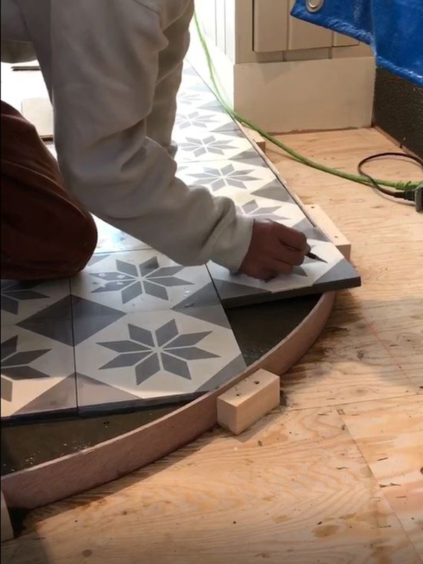 カーブに合わせてカットする為に、フリーハンドでラインを描いています carreau cimentのエトワール柄の床がフレンチなカフェ,施工例,店舗プランニング,アンティークタイル,モルタル床,3